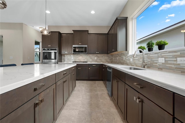 kitchen featuring decorative backsplash, stainless steel appliances, sink, dark brown cabinetry, and decorative light fixtures