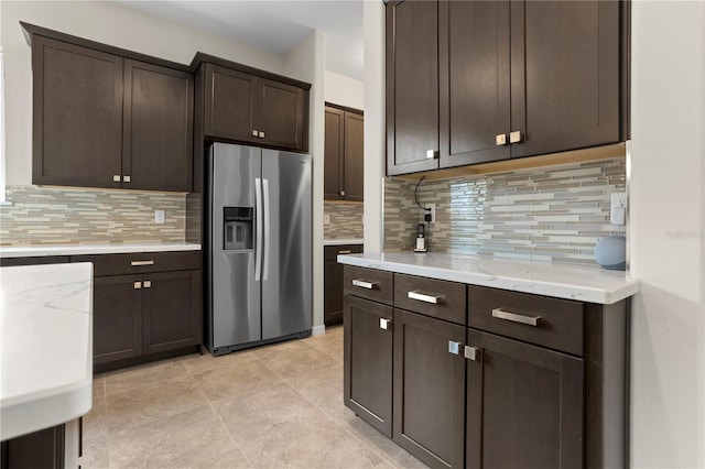 kitchen featuring tasteful backsplash, dark brown cabinets, and stainless steel fridge