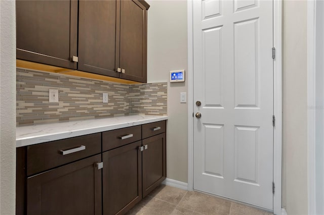 interior space featuring decorative backsplash, light stone counters, dark brown cabinets, and light tile patterned floors