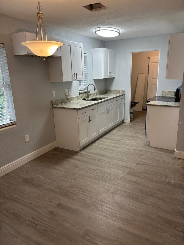 kitchen featuring pendant lighting, light hardwood / wood-style floors, white cabinetry, and sink