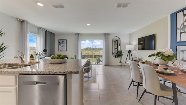 kitchen featuring stainless steel dishwasher, a wealth of natural light, light stone countertops, and white cabinets