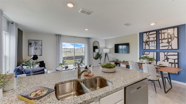 kitchen with light stone countertops, white cabinets, dishwasher, and sink