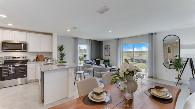 kitchen with white cabinets, sink, light tile patterned floors, appliances with stainless steel finishes, and light stone countertops