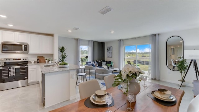 kitchen featuring white cabinets, light tile patterned flooring, sink, stainless steel appliances, and light stone countertops