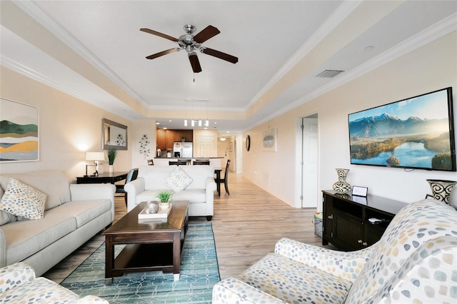 living room with ornamental molding, a tray ceiling, ceiling fan, and hardwood / wood-style floors