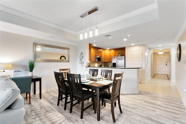 dining room with ornamental molding and light hardwood / wood-style floors