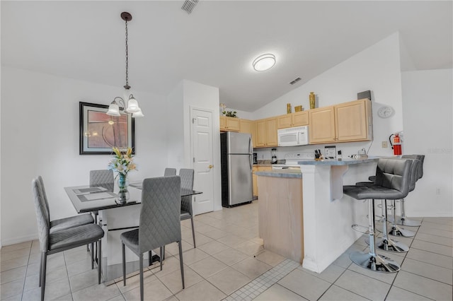 kitchen featuring stainless steel refrigerator, light brown cabinets, kitchen peninsula, lofted ceiling, and range