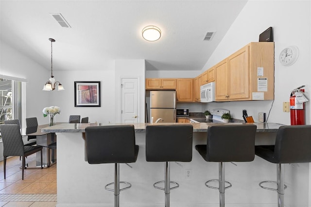 kitchen featuring visible vents, freestanding refrigerator, lofted ceiling, and white microwave