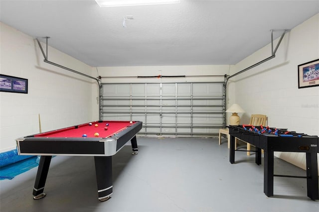 rec room with a garage, concrete flooring, concrete block wall, and billiards