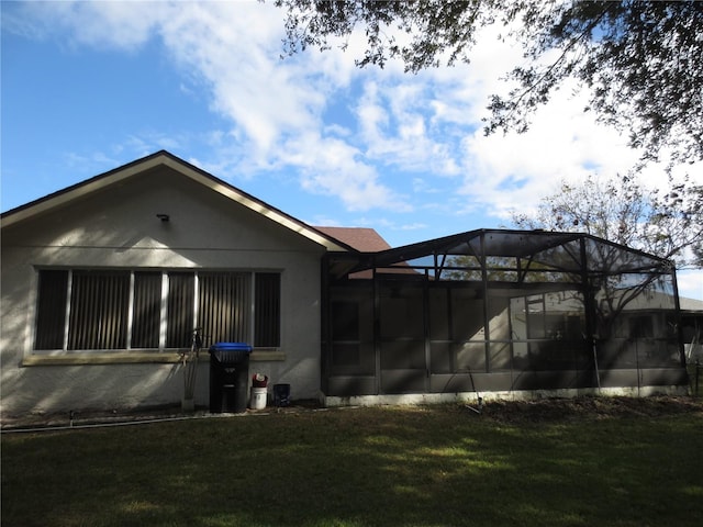 rear view of house with a lanai and a lawn