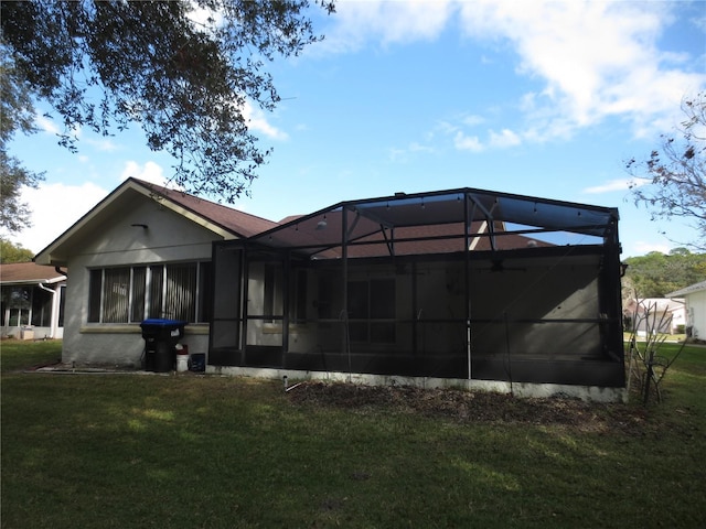 rear view of house featuring glass enclosure and a yard