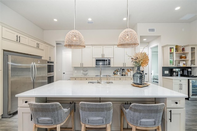 kitchen featuring stainless steel appliances, an island with sink, and pendant lighting