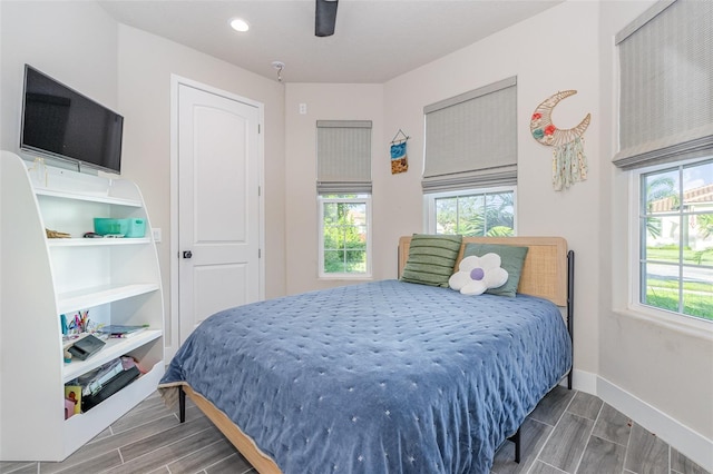 bedroom featuring ceiling fan, multiple windows, and dark hardwood / wood-style flooring