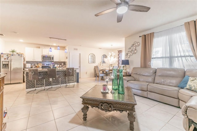 tiled living room featuring ceiling fan with notable chandelier