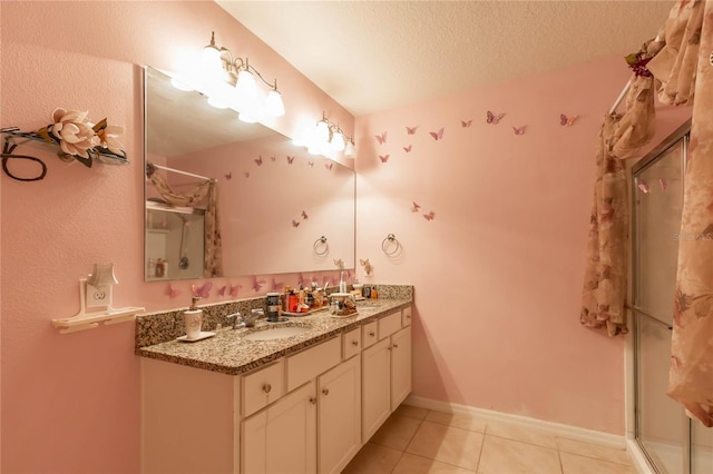 bathroom featuring vanity, a shower with shower door, a textured ceiling, and tile patterned floors