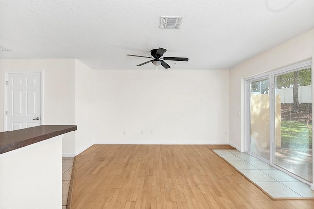 unfurnished room featuring a textured ceiling, light wood-type flooring, and ceiling fan