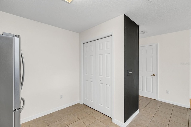 kitchen featuring stainless steel fridge, a textured ceiling, and light tile patterned floors