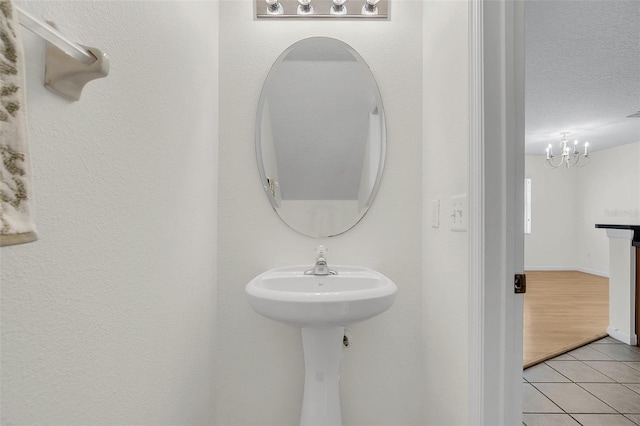 bathroom with a notable chandelier, a textured ceiling, and tile patterned flooring