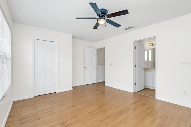 unfurnished bedroom featuring a closet, ensuite bath, light hardwood / wood-style flooring, and ceiling fan