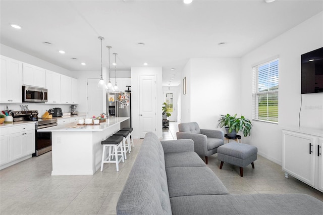 kitchen featuring white cabinets, a kitchen island with sink, stainless steel appliances, and a kitchen bar