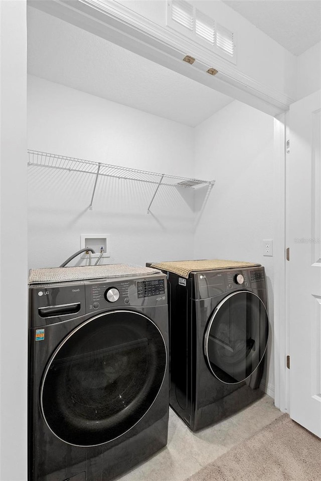 clothes washing area with washing machine and clothes dryer and light carpet