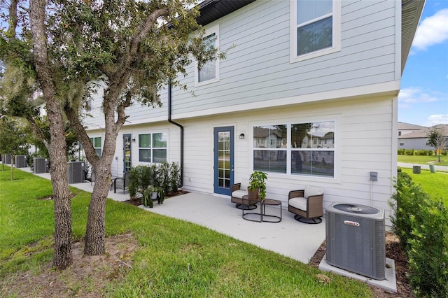 rear view of property featuring a lawn, a patio area, and central air condition unit