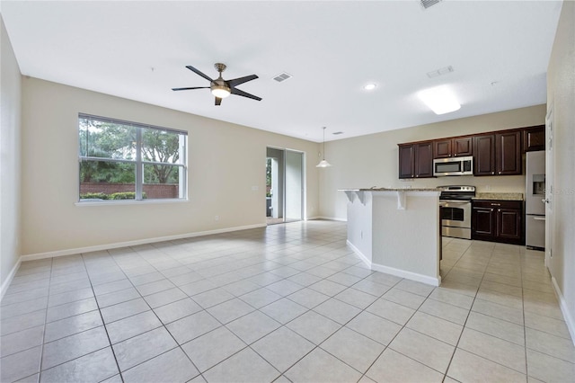 kitchen with a kitchen breakfast bar, light tile patterned flooring, decorative light fixtures, and stainless steel appliances