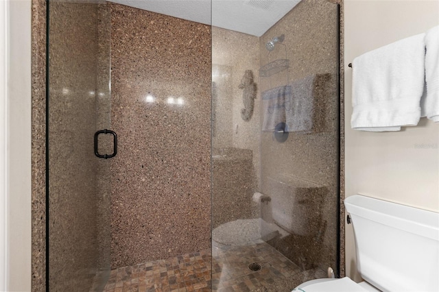 bathroom with a textured ceiling, toilet, and a shower with shower door