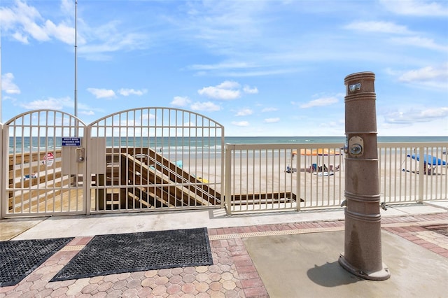 view of gate featuring a view of the beach and a water view