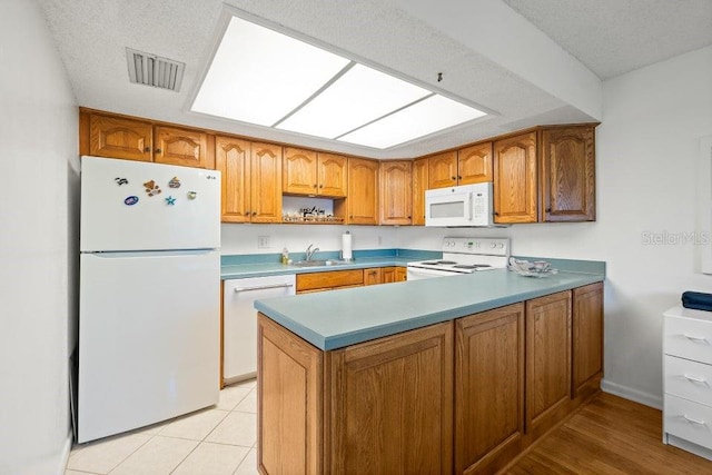 kitchen with a textured ceiling, sink, light tile patterned floors, and white appliances