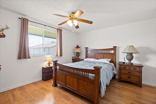 bedroom with a textured ceiling, light wood-type flooring, and ceiling fan