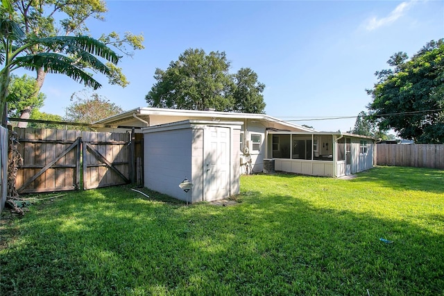 rear view of property with a storage shed, a yard, and a sunroom