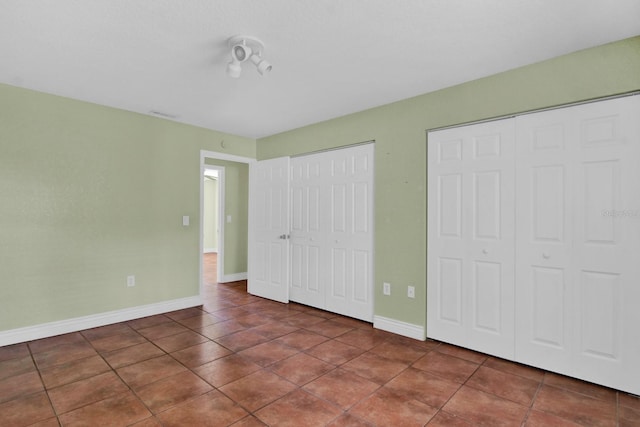 unfurnished bedroom with multiple closets and dark tile patterned floors