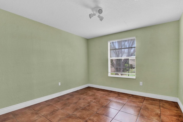 empty room featuring a textured ceiling and tile patterned flooring