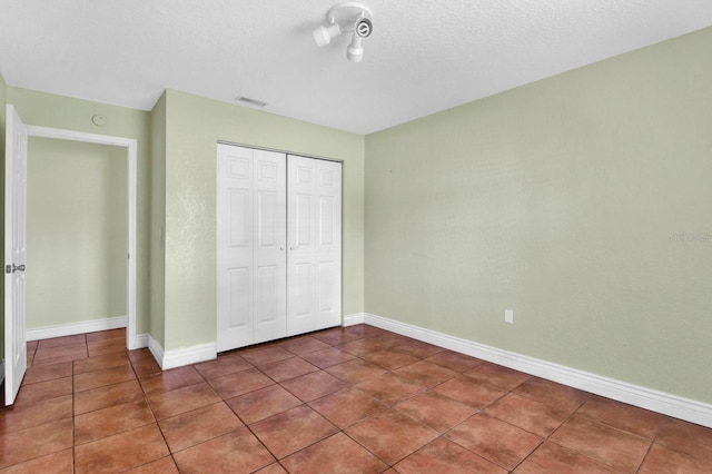 unfurnished bedroom featuring a closet, a textured ceiling, and tile patterned floors