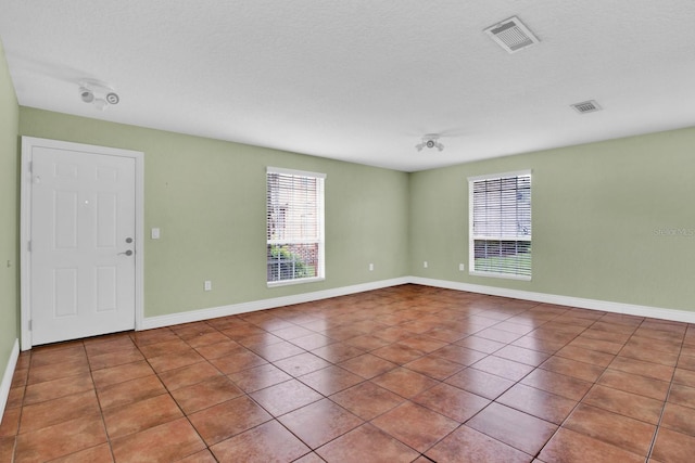 empty room with a wealth of natural light and tile patterned floors