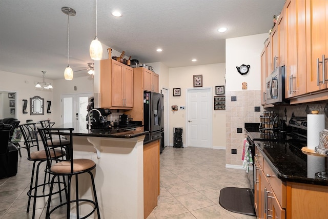 kitchen featuring hanging light fixtures, light tile patterned floors, tasteful backsplash, stainless steel appliances, and a breakfast bar area