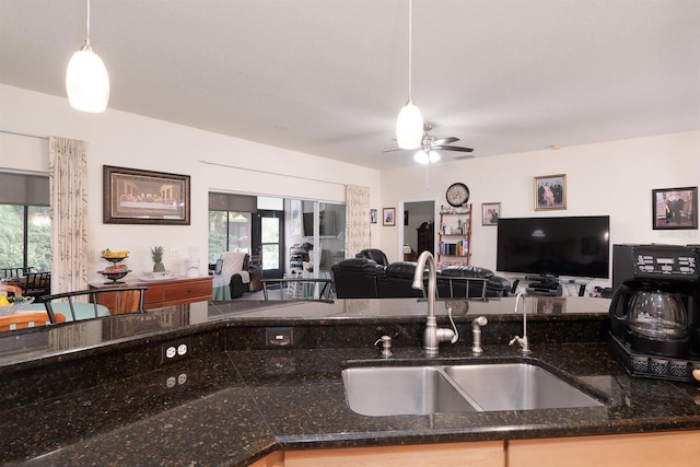 kitchen with dark stone countertops, sink, ceiling fan, and decorative light fixtures