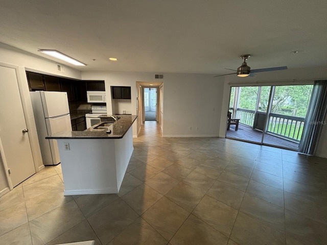 kitchen featuring light tile patterned flooring, white appliances, ceiling fan, a center island with sink, and sink