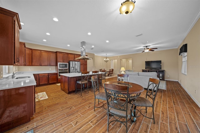 dining space featuring ceiling fan with notable chandelier, ornamental molding, sink, and light hardwood / wood-style flooring