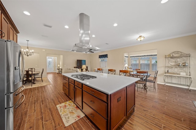 kitchen featuring ornamental molding, wood-type flooring, island exhaust hood, appliances with stainless steel finishes, and a center island