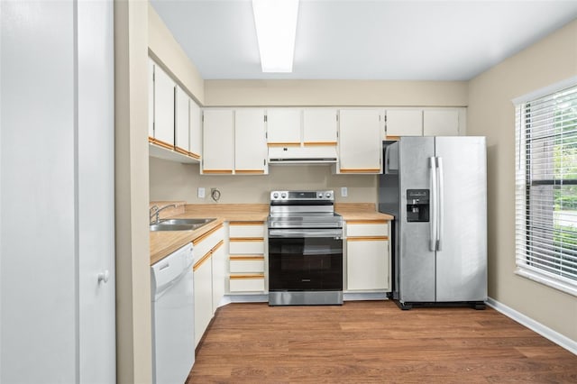 kitchen with white cabinets, stainless steel appliances, sink, and light hardwood / wood-style flooring