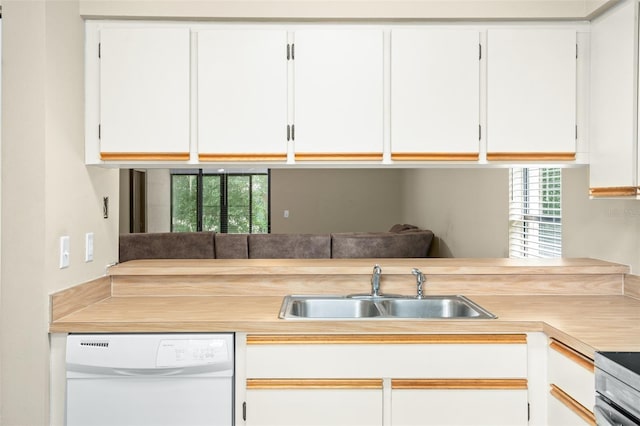 kitchen with white cabinetry, kitchen peninsula, white dishwasher, sink, and stainless steel range