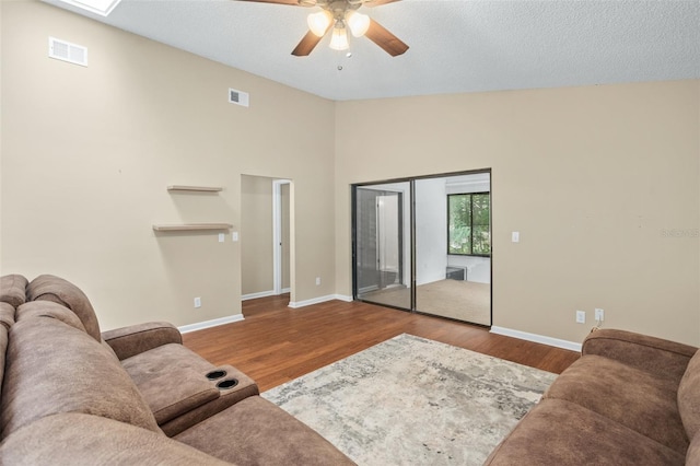 living room with high vaulted ceiling, ceiling fan, hardwood / wood-style floors, and a textured ceiling