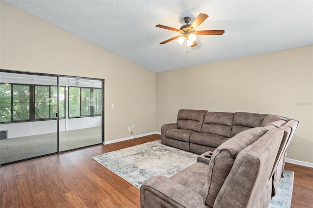 living room featuring a textured ceiling, vaulted ceiling, dark hardwood / wood-style flooring, and ceiling fan