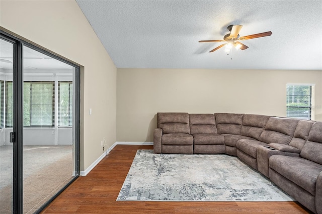 living room with a healthy amount of sunlight, vaulted ceiling, ceiling fan, and dark wood-type flooring