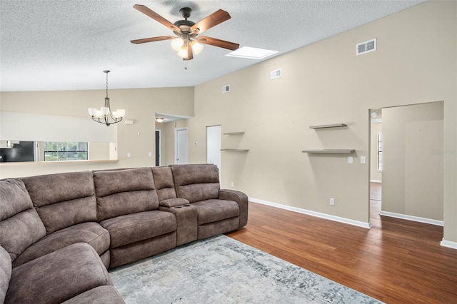 living room featuring ceiling fan with notable chandelier, vaulted ceiling with skylight, a textured ceiling, and hardwood / wood-style floors