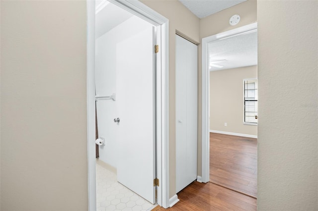 hallway featuring light wood-type flooring and a textured ceiling