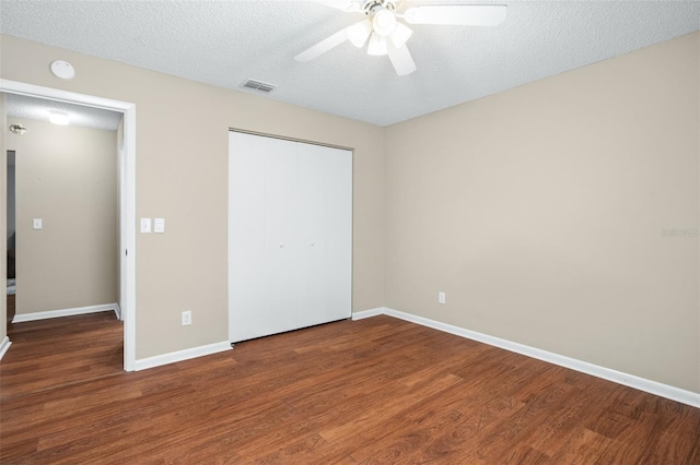 unfurnished bedroom featuring a closet, ceiling fan, dark wood-type flooring, and a textured ceiling