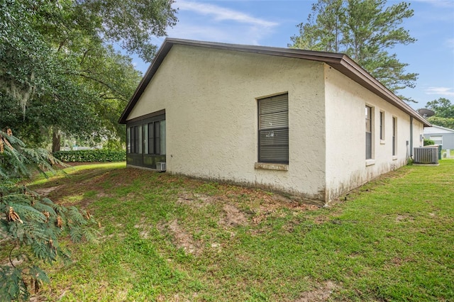 view of side of property featuring a yard and central AC